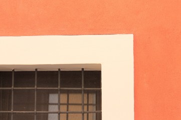 Window details with gratings of an orange house wall - Architectural background (Marche, Italy, Europe)