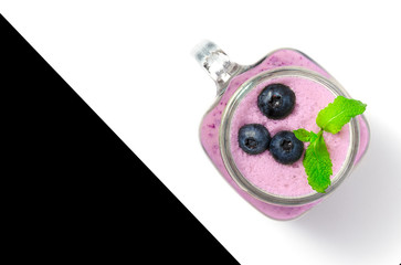 Blueberry smoothie with mint in mason jar glass with berries and mint. Above view on white table. Healthy food.