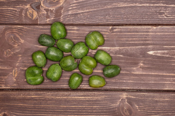 Lot of whole fresh green mini baby kiwi fruit close to each other flatlay on brown wood