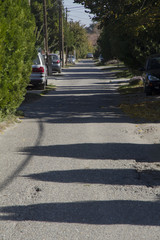 A perspective shot of a narrow street with shadow play on the asphalt road. Urban scene.