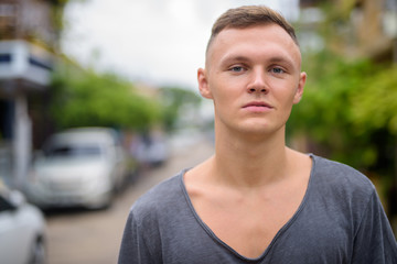 Young man wearing gray shirt in the streets outdoors