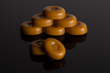 Group of eight whole caramel cream candy butterscotch variety on black glass