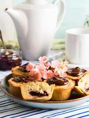 Cakes with frangipane, cherry jam and chocolate frosting. Romantic table setting with flowers. Mother's day card