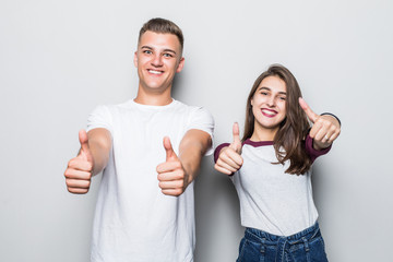 Portrait of happy young couple putting thumbs up on white background