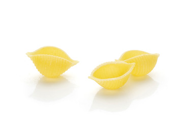 Group of three whole traditional raw yellow pasta conchiglie variety isolated on white background