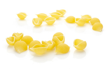 Lot of whole raw yellow pasta conchiglie variety front focus isolated on white background