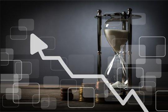 Sand running through the bulbs of an hourglass on business chart