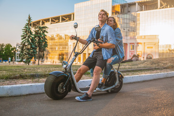 Lovely young couple driving electric bike during summer Modern city life and transportation