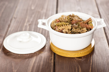 Raw pasta fusilli on brown wood