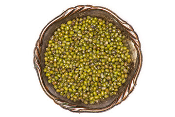 Lot of whole dry green mung beans in old iron bowl flatlay isolated on white background