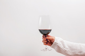 Womans hand in knitted sweater holding a glass of red wine