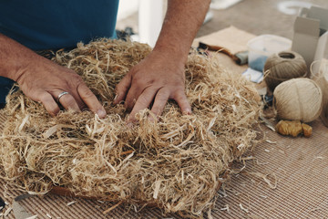 An upholsterer shapes flax with his hands for a chair upholstery - 228105018