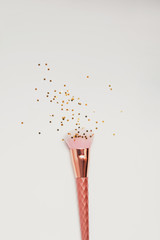 Pink make-up brush with small colden stars on the white background.