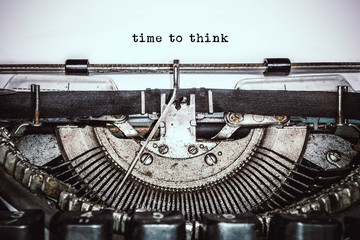 Old vintage typewriter, retro machine with white sheet of paper and typed text "time to think", copy space, close up