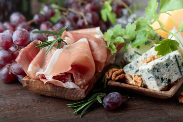Various cheeses , grapes and prosciutto .