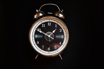 Iron clock with arrows on black background. 