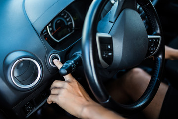 Finger of man press start button engine of car with black color interior of car