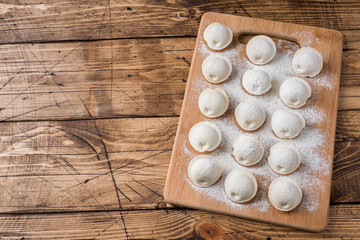 Fototapeta na wymiar Raw dumplings on a wooden chopping Board in the kitchen Copy space
