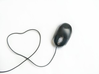 Black laptop mouse with cable line in heart shaped on isolated white background, high angle view...