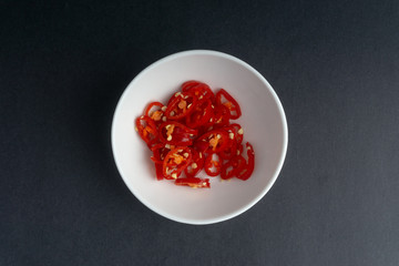 Red chili slices on dark background with selective focus and crop fragment