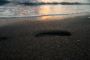 Fototapeta na wymiar Footprints on the sea sand at sunset
