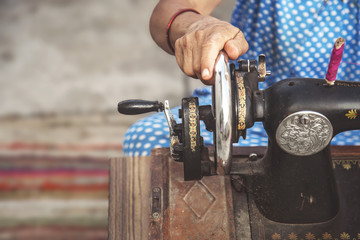 close up image of lady hands sewing her cloth with  old sewing machine