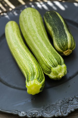 drei Gartenzucchinis auf einem schwarzen Teller