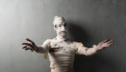 Fototapeta na wymiar Terrorific mummy on textured wall presenting halloween holidays