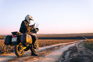 Motorbiker travelling, autumn day, motorcycle off road, rider, adventurer, extreme tourism, cold weather clothes, uses smartphone, internet, search,
