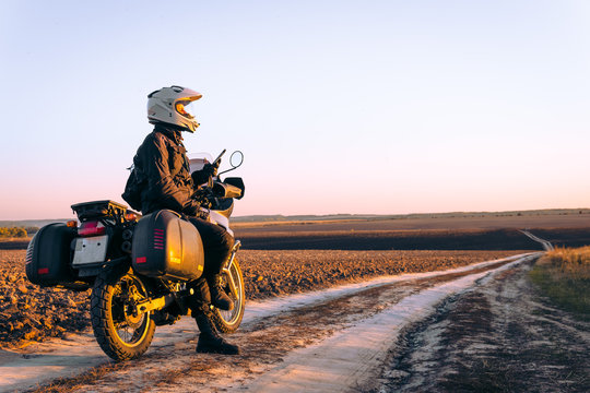 Motorbiker travelling, autumn day, motorcycle off road, rider, adventurer, extreme tourism, cold weather clothes, uses smartphone, internet, search,