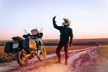 Motorbiker travelling, autumn day, motorcycle off road, rider, adventurer, extreme tourism, cold weather clothes, uses smartphone, internet, search, find, lost the signal, light tinting