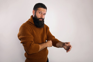Ready for hard work! Bearded man in casual warm knitted sweater preparing to work hard, adjusting sleeves, copy space, gray studio background