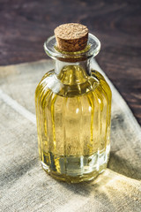 Glass bottle with vegetable oil on wooden background