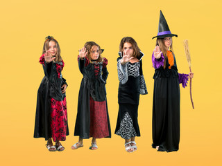 Set of Little girl dressed as a vampire for halloween holidays making stop gesture with her hand on orange background
