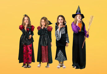 Set of Little girl dressed as a vampire for halloween holidays showing a sign of closing mouth and silence gesture on orange background