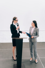 Fototapeta premium high angle view of attractive lecturer looking at smiling assistant during seminar in conference hall