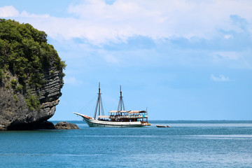 Obraz premium White sailboat in the ocean with views of the island and the blue sky