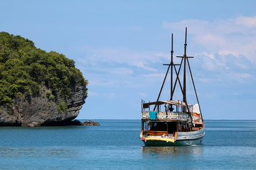 White sailboat in the ocean with views of the island and the blue sky