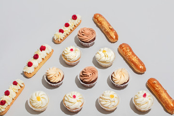 Muffins and eclaris composed in triangular shape.