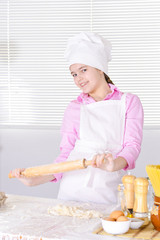 Cute girl in chef's hat baking cake in the kitchen