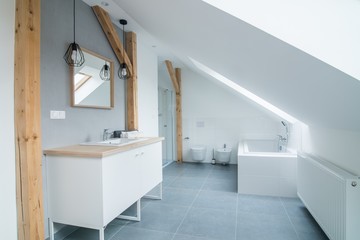 Bright modern bathroom with grey walls, mirror and bathtub.