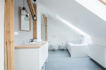 Bright modern bathroom with grey walls, mirror and bathtub.
