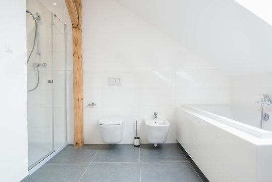 White loft bathroom with glass shower cabin.