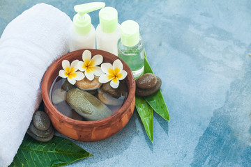 Obraz na płótnie Canvas Tropical flowers, bowl of water, towel and cream tubes. Body care and spa concept on marble background