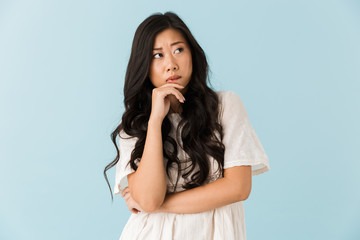 Thinking young asian beautiful woman posing isolated over blue background.