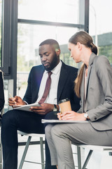 multiethnic business colleague sitting on chairs during business seminar in conference hall