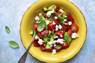 Vegetable salad with avocado, cherry tomato, grilled bell pepper and feta.Top view.