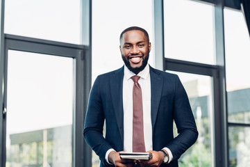 smiling african american businessman with notebook in conference hall