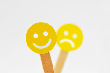 Smiley face with positive expression in front of out of foucs sad face - Positivity concept