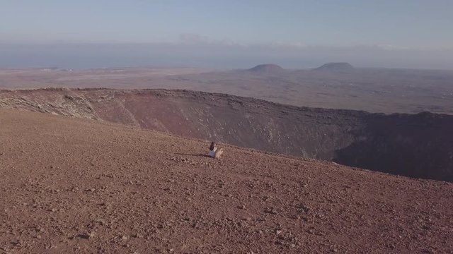 young girl together with her dog on the top of the volcano